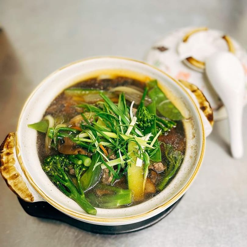 A Japanese hot pot dish from Soi Bistro, with broth, meat, and fresh green vegetables.